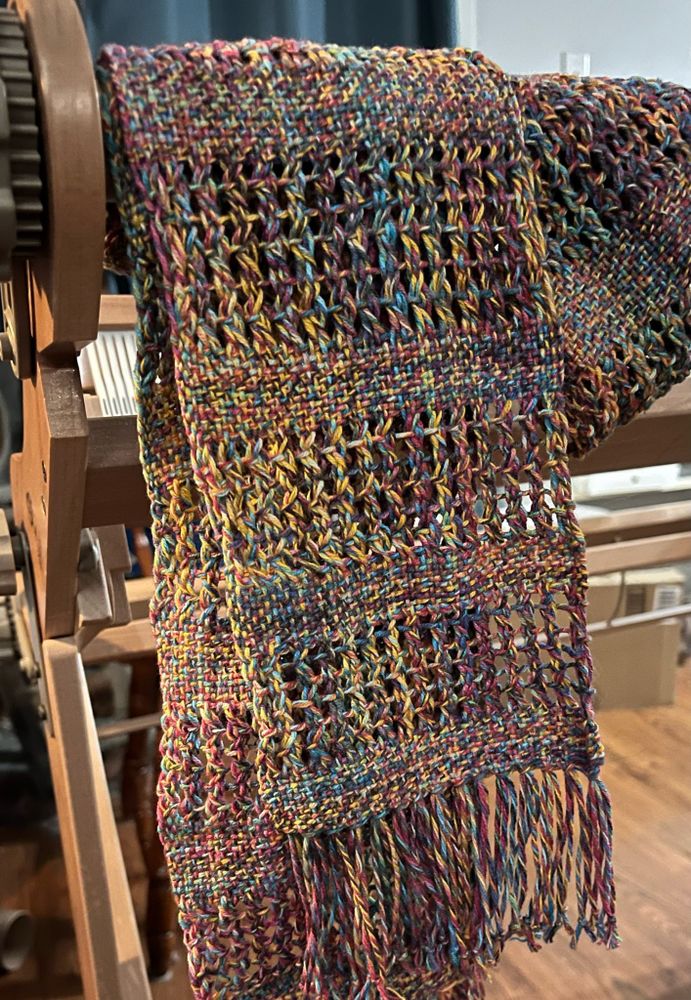 Colourful hand-woven cotton scarf hung over a rigid heddle loom.