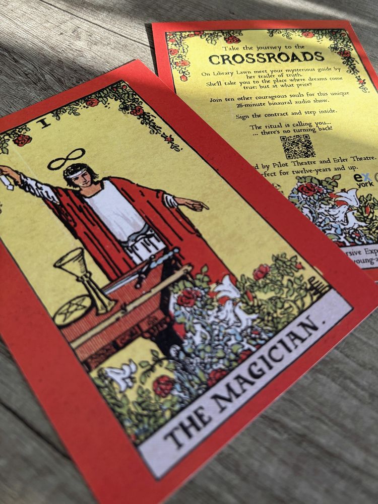 A Tarot card with The Magician on the front is overlapping another card that has a similar design of colourful flowers overlaid onto a yellow background which has information about the show written on it.