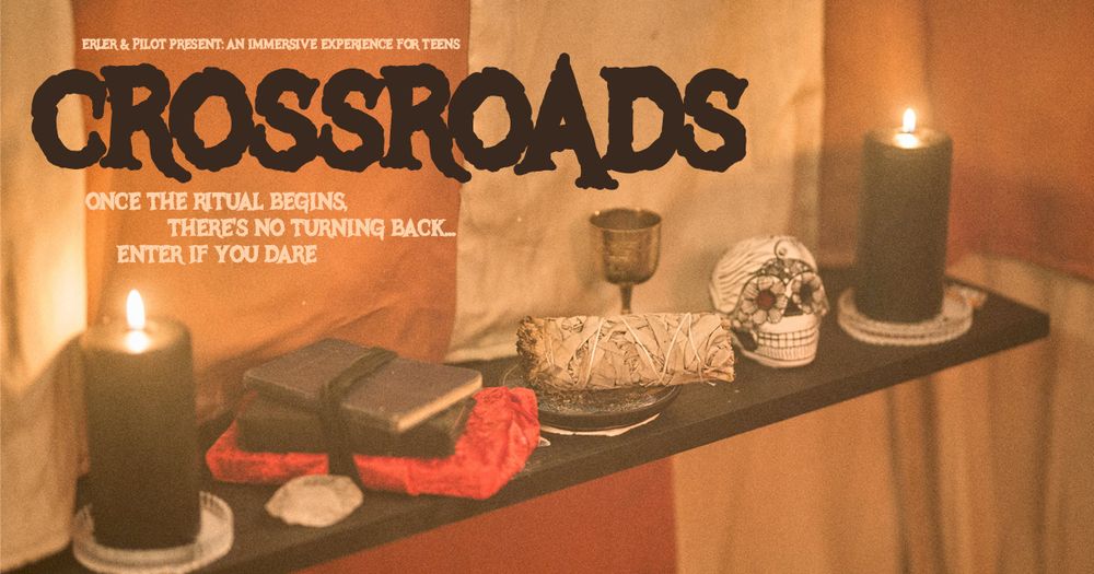 Striped fabric draped down the walls of an unknown space. On a wooden shelf are lit candles, a decorated paper skull, leather-bound books, an incense stick, and a chalice.