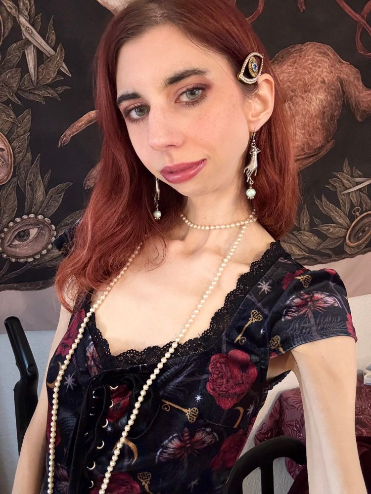 Photo of me in a long strand of pearls, a velvet floral dress, and a hair pin with an eyeball pattern on it