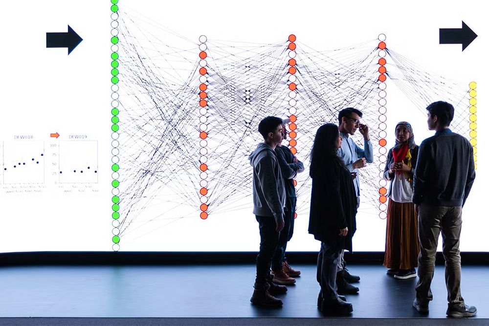 A group of researchers exchanging ideas in front of a large digital display