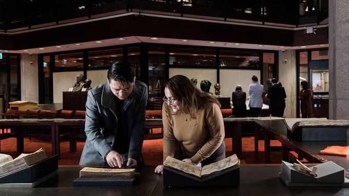 Two people examining a book inside the Thomas Fisher Rare Book Library
