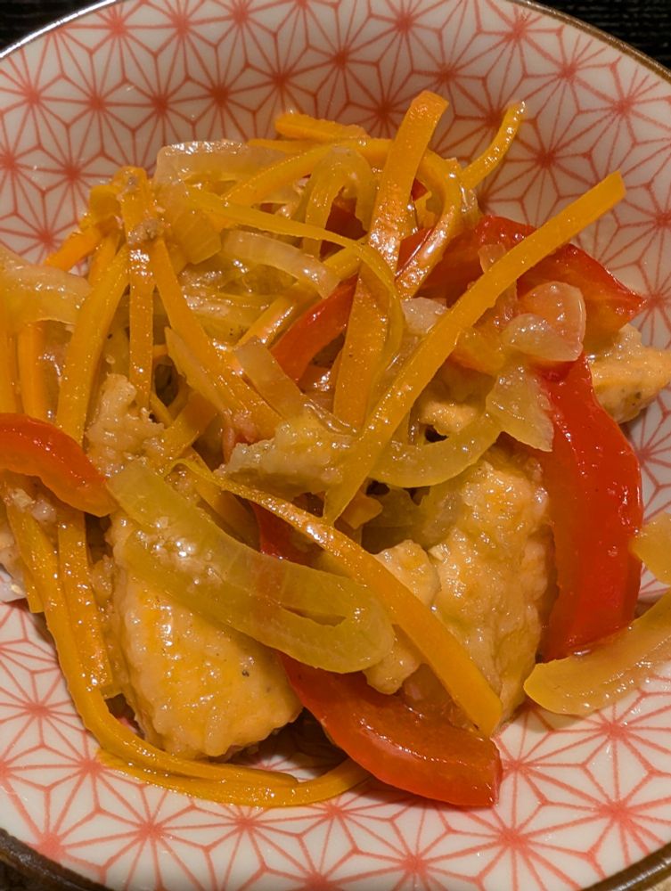 pan-fried salmon nuggets topped with sauteed veggies over rice in a red and white bowl. the fish and veggies have been marinated in a vinegar-based sauce. 