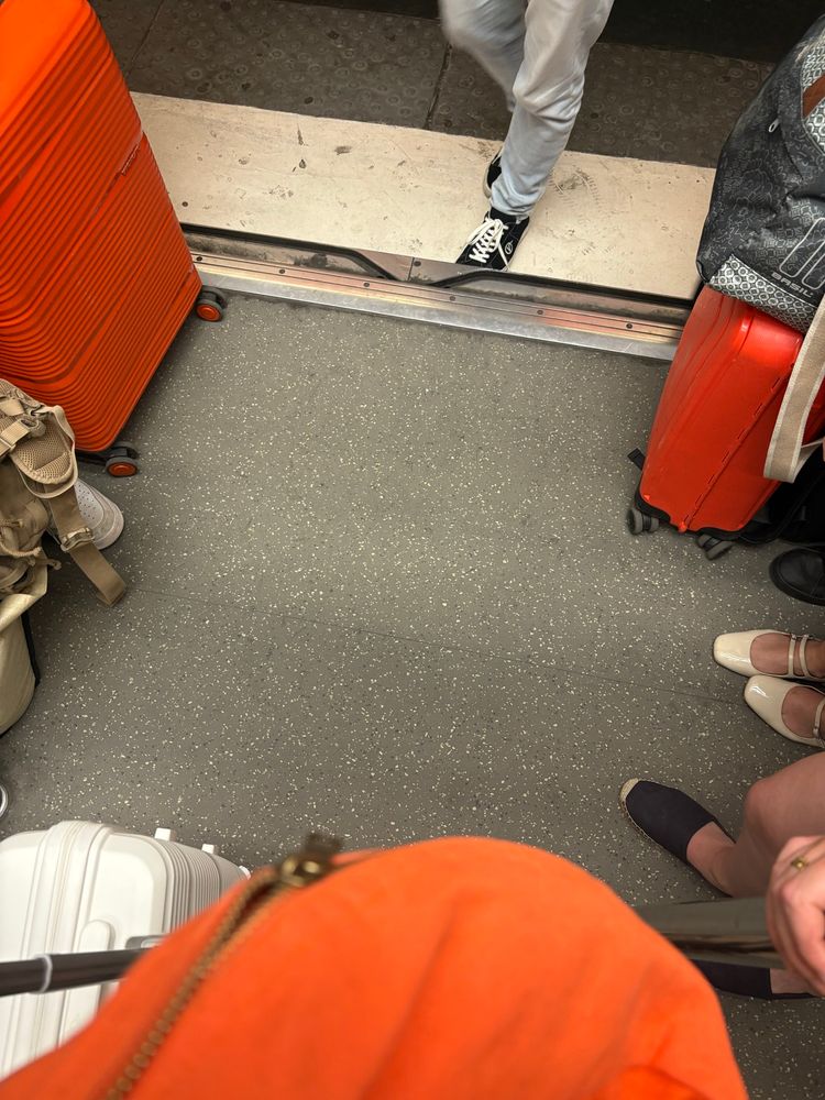 Dans le métro, on voit de part et d’autre deux valises oranges et ma banane orange également au premier plan.