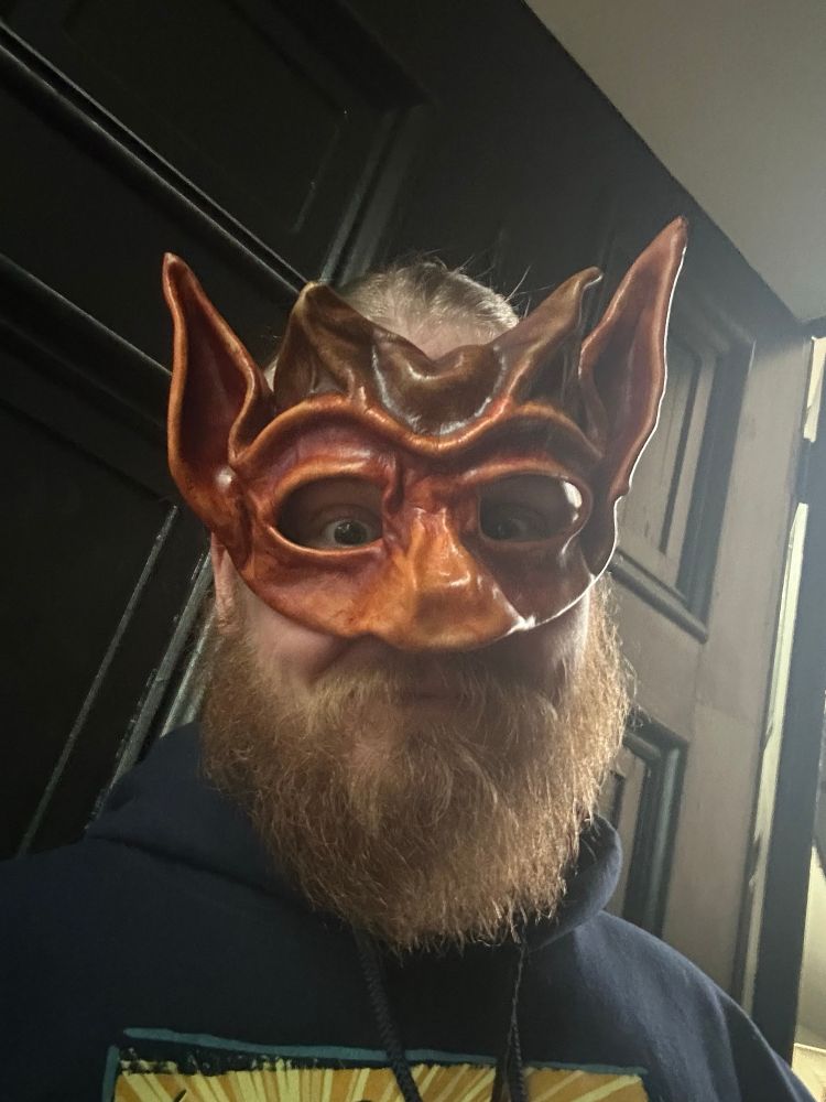 A photo of a bearded blonde person wearing a leather satyr / goat demon mask