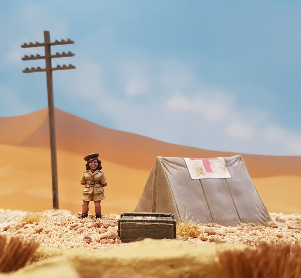 28mm diorama of vera lynn in the desert by a first aid tent. Vera is sculpted by Alan Marsh and painted by John Morris. The backdrop is a smooooth desert