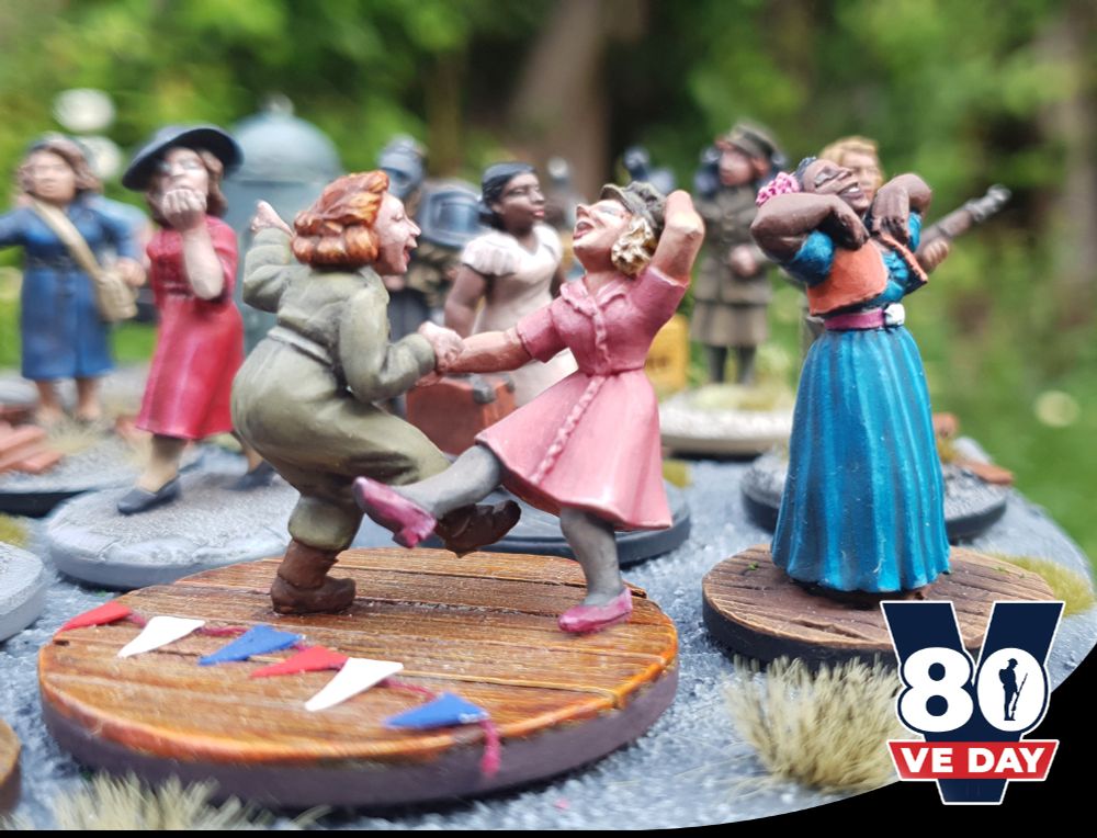 It's VE Day! Victory in Europe, 80 years! Here's one of my favourite sets from our Bad Squiddo Games range - a lady is finally home from serving away in the ATS and her girlfriend couldn't be more delighted, she pinches her hat playfully while they celebrate the end of the war.

These are currently on one of our micro diorama slabs that show off the ranges, so I took the photo as they are arranged (and I don't want to jinx breaking them so soon to UKGE) , and something poignant came out of it.

Noor Inyat Khan was in the way.

When taking this sort of photo I would keep the space behind them fairly plain so it focuses on them, but these minis are currently fixed down, so I was trying to find the right angle.

But then it occured to me - she isn't in the way at all.

You can't have the celebration without remembrance.

Noor was shot by the nazis before the war was over and so never made any of the celebrations, though her contribution as an SOE agent helped make it possible, much like the many, many millions lost in WW2.

We must remember those who fought fascism, their stories, their motives and their actions, and honour what they did by carrying it on.

Also in the shot we have a kiss blowing SOE Nancy Wake, who did thankfully live to a ripe old age (and tell her many incredible stories), and also a singing Josephine Baker who not only worked with the resistance in France, but after the war returned to America to continue the fight against segregation and racism- even speaking right before Martin Luther King Jr at the March on Washington.

We will remember them.
