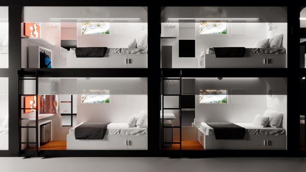 Modified alttexty.org: Rendered cross-section of four contemporary sleeping units in a hostel. Each unit, decorated in white, has a bed with a dark blanket, pillows, a fake window, and built-in storage, as well as a table and TV. Black support beams and ladders connect the floors.