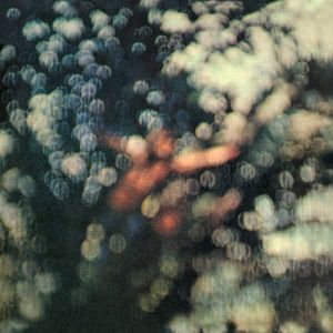 The cover to the album "Obscured by Clouds," by Pink Floyd.  It's a very intentionally out of focus and blurry image of what appears to be a tree with the light from the sky poking through at hundreds of points in the gaps of the leaves and branches, and possibly a person in the center that almost resembles the trunk of the tree itself.