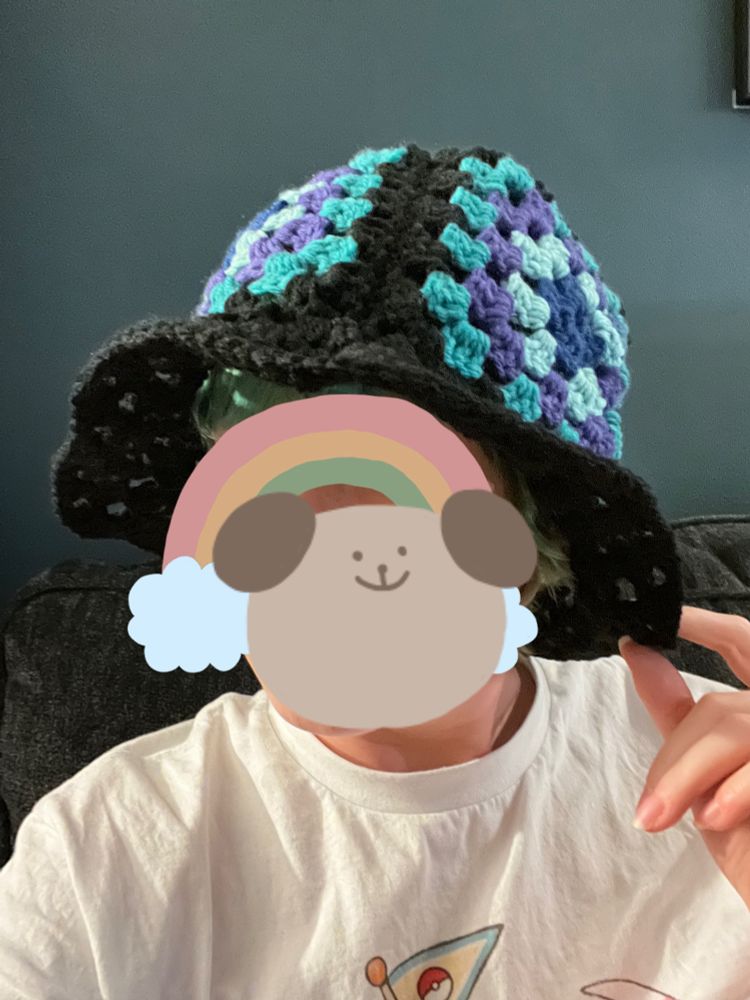 Showing off a black, blues, and purple crochet bucket hat made with granny squares