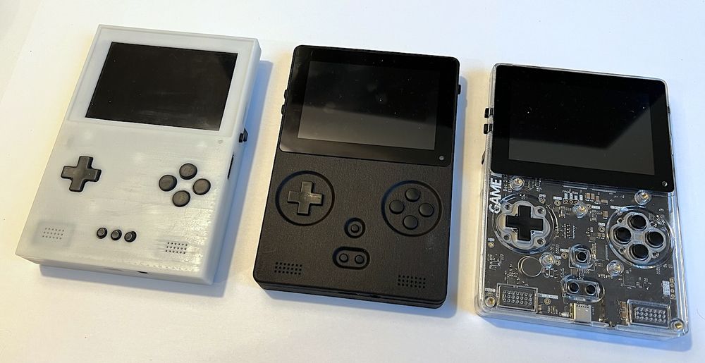 photo of 3 game bub consoles, opaque white case, black case, transparent case