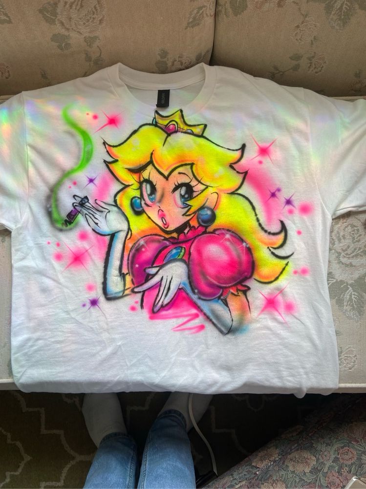 Airbrushed white tshirt. Design has Princess Peach smoking a purple joint.