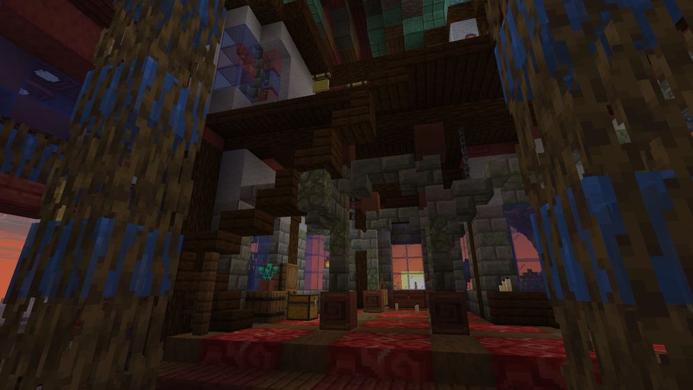 Another interior shot of the same building, looking between two pillars made of waterlogged mangrove roots toward the red glazed terracotta section of the floor. That area looks a little bit like an old church, repurposed. There are also stairs leading up to an open loft.