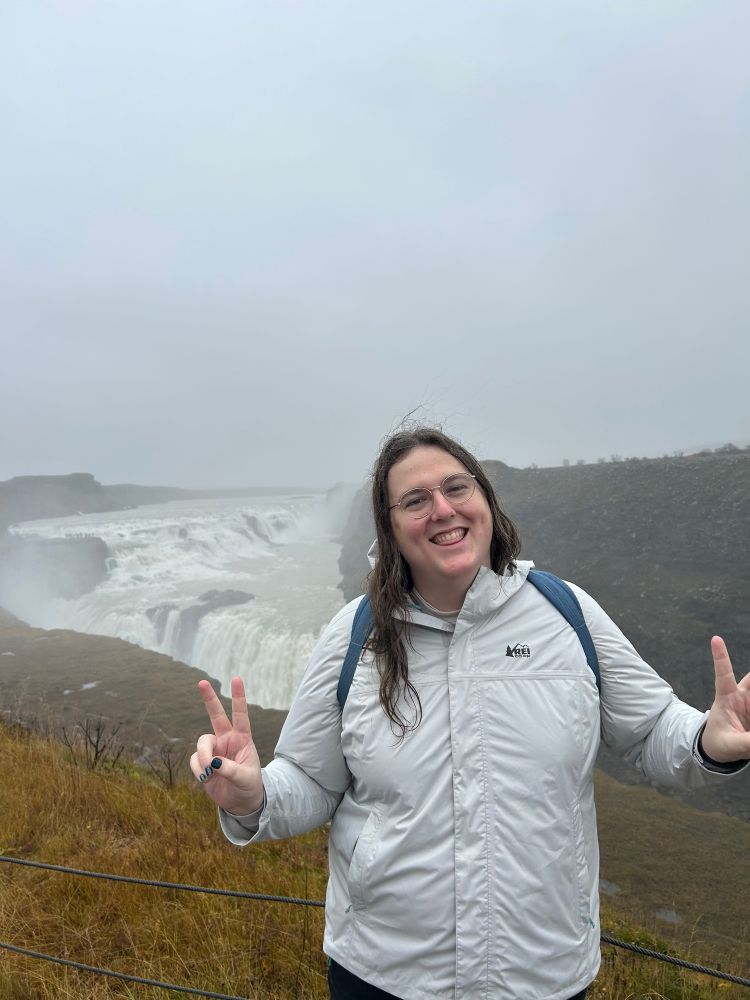 a picture of the poster posing in front of a giant waterfall 