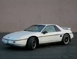 A picture of a white Pontiac Fiero. We had one when I was a kid that looked just like this. It sat in our driveway and rotted. My dad and I both used it as our secret cigarette smoking place. 