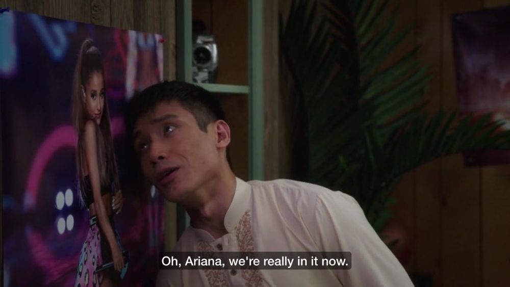 Screen grab of The Good Place: Jason leans his head despairingly against a poster of Ariana Grande. His eyes are soulful and pathetic. The caption reads, "Oh, Ariana, we're really in it now.".