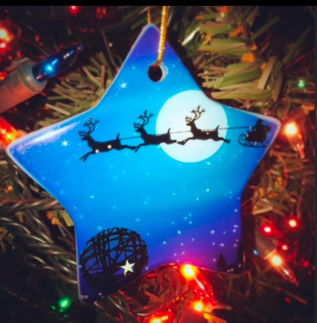 Star shaped holiday ornament with an image of the twine ball on the ground and Santa’s sleigh being pulled across the night sky. 