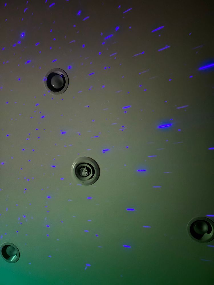A white ceiling speckled with bright blue “stars” from a galaxy projector.