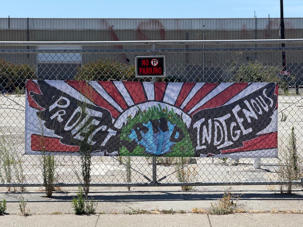 Sign on a fence saying “protect indigenous land.”