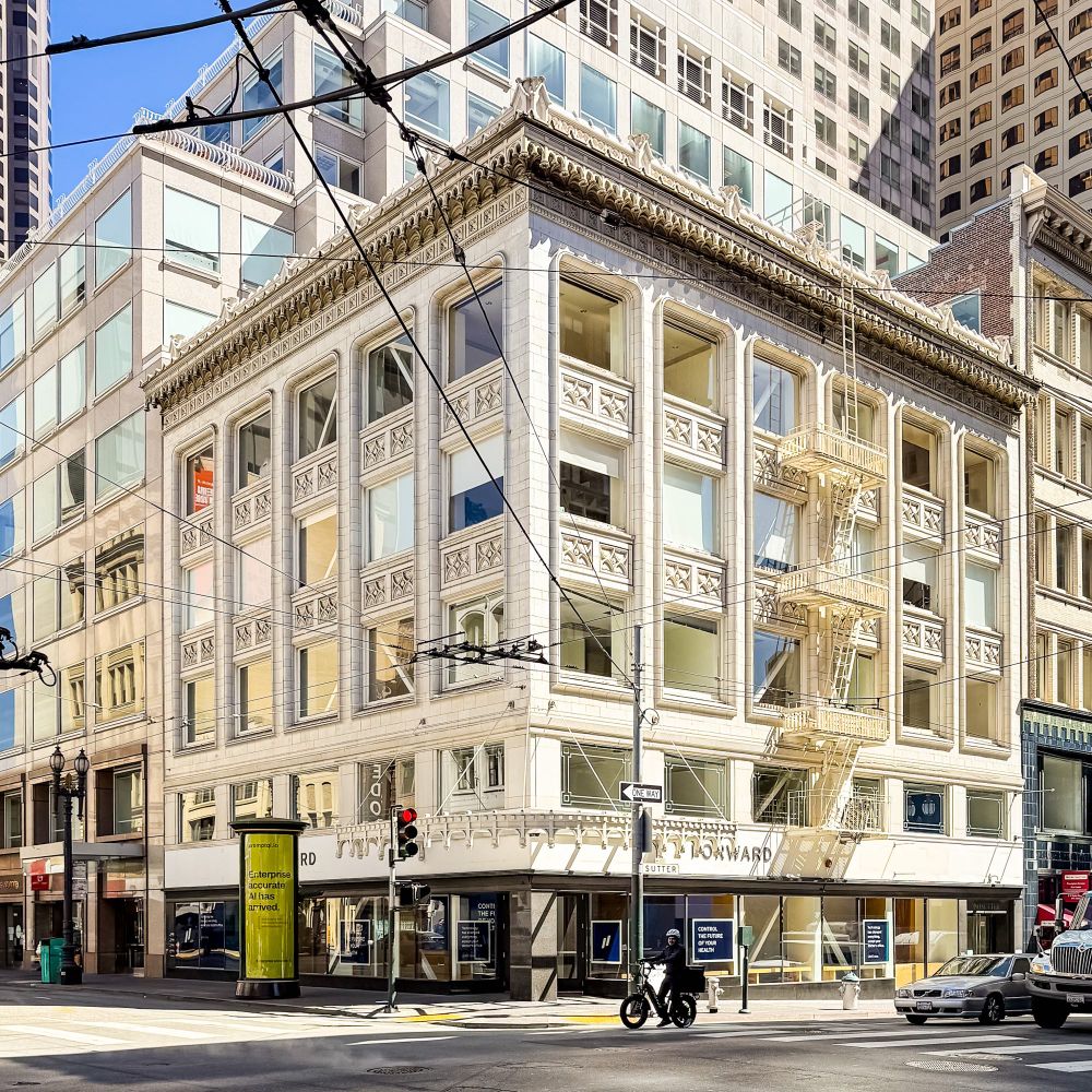 A commercial building in downtown San Francisco with a very detailed white stone facade and cornice. 