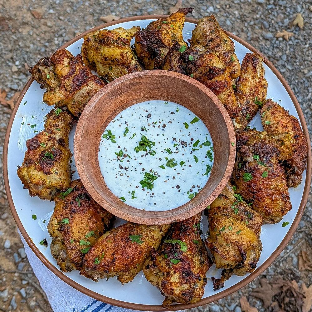White round plate, chicken wings circling a wooden bowl full of ranch. 