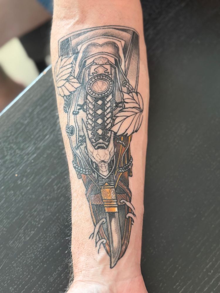 An assassin’s creed tattoo of the AC Shadows hidden blade.