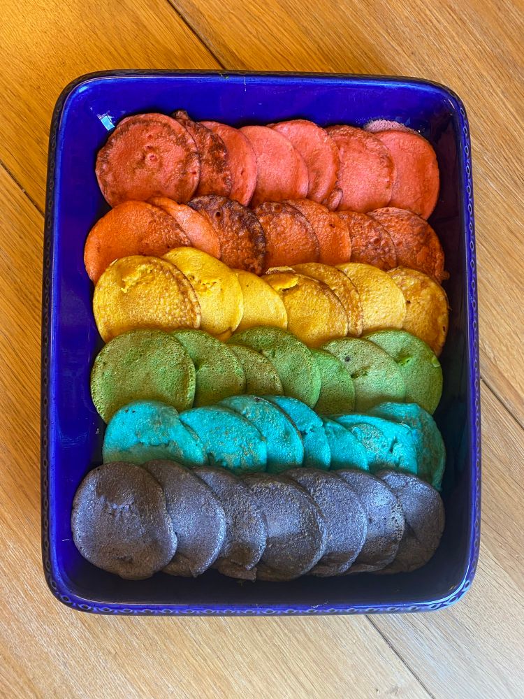 Ett fat med plättar i regnbågens alla färger. 