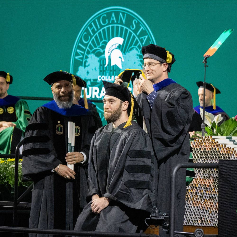 An MGI PhD student receives his hood from his advisor. 
