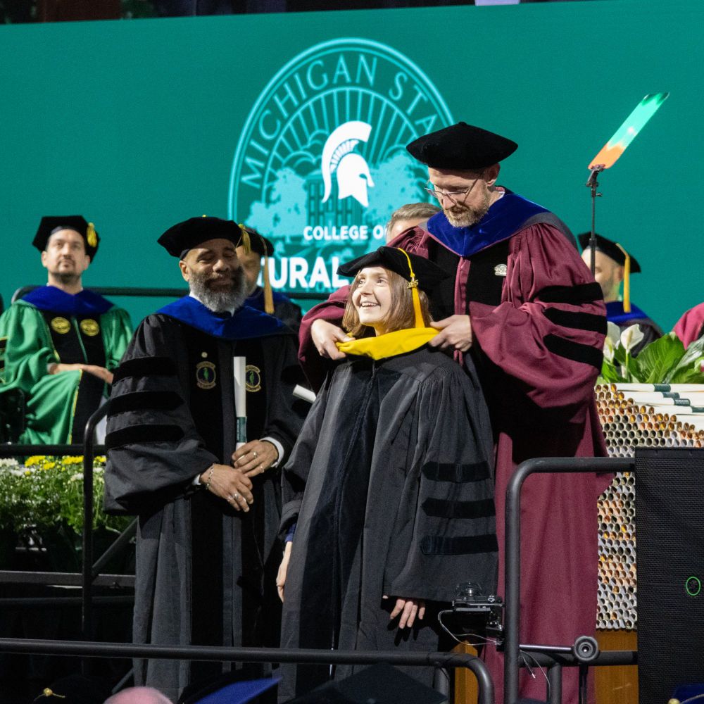 An MGI PhD student receives her hood from her advisor. 
