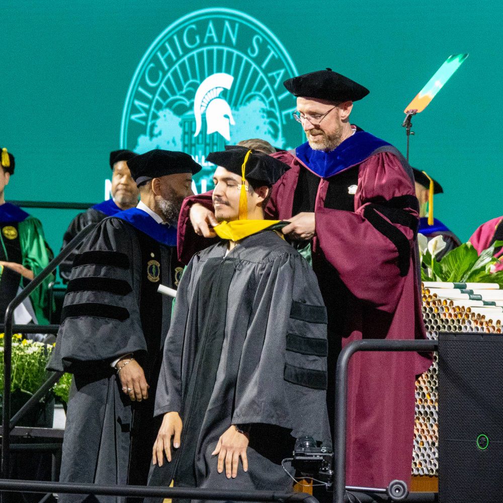 An MGI PhD student receives his hood from his advisor. 
