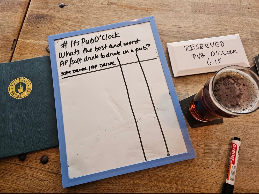 Whiteboard on a pub table with the question "What's the best and worst AF drink or soft drink to drink in the pub. Reserved: pub o clock 6.15. Pint.