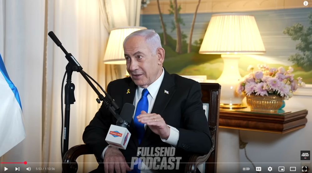 screenshot of genocidaire benjamin netanyahu on the full send podcast with a happy dad mic flag 