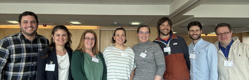 Eight researchers posing smiling in a university room