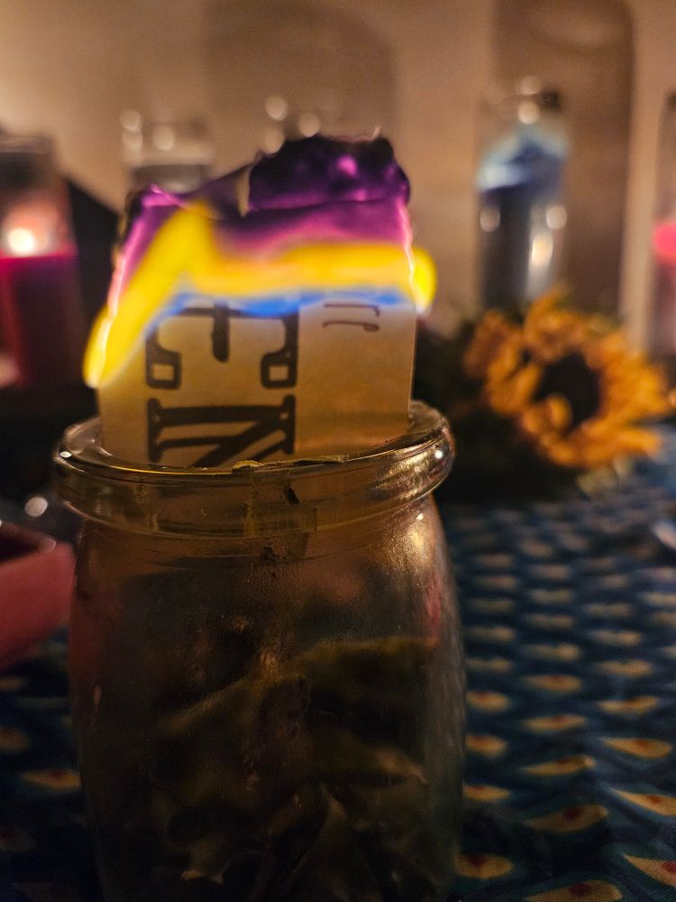 A paper with writing on it burns inside a jar on an altar. 