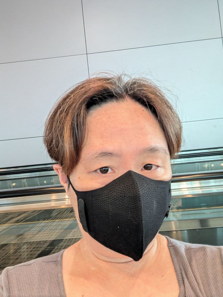 An Asian with light brown highlights with a black mask. 