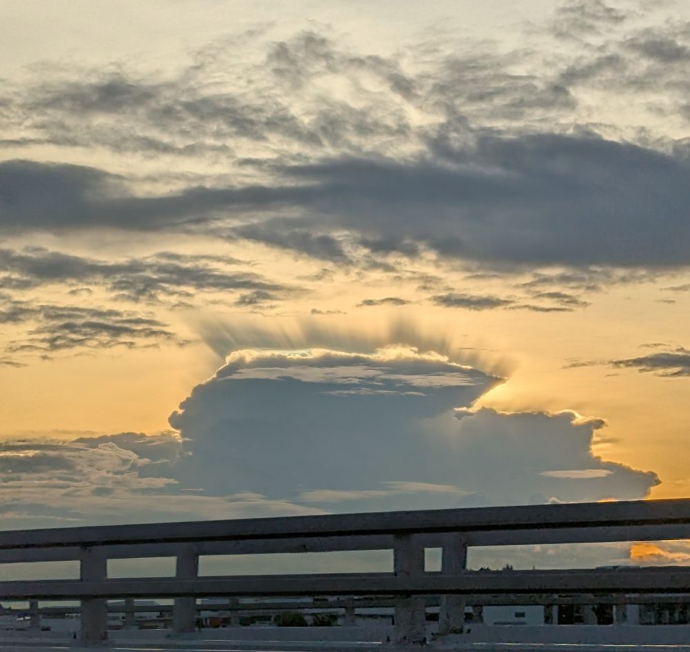 Clouds at sunset, with a thunderhead shimmering with rays. 