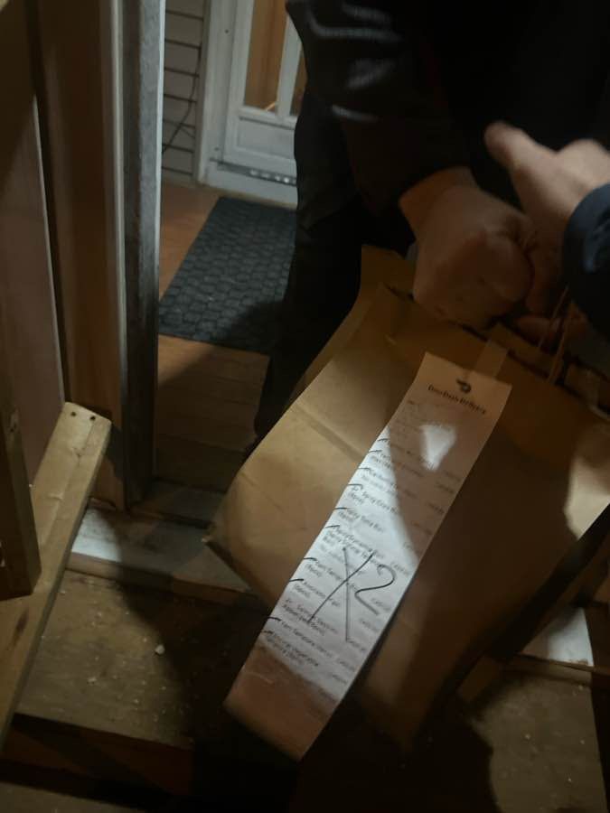 A nice photo of a delivery person trying to hand over a couple bags of food, and my hand gripping the handles and almost taking his fingers with them as I pull them away. 