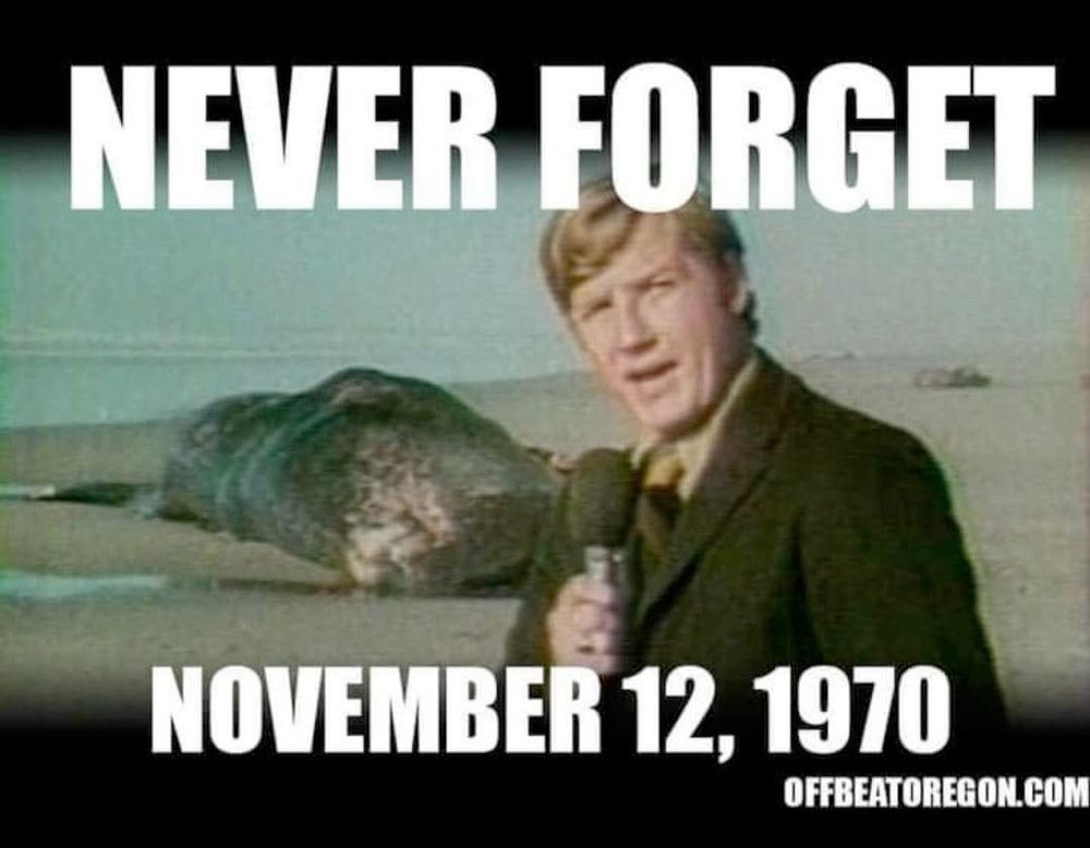 A reporter at stands in the foreground with a dead whale in the background with the words "never forget, November 12, 1970.