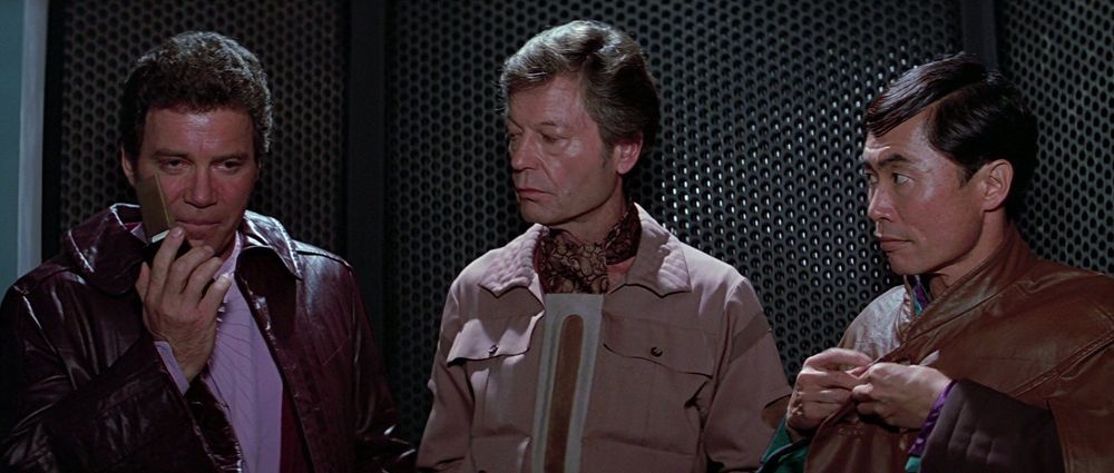William Shatner wearing a sick red jacket, DeForest Kelly wearing a sick brown jacket, and George Takei wearing a sick brown jacketlike cloak, all from one of the Star Trek Movies (I think Star Trek 4: The Voyage Home) 