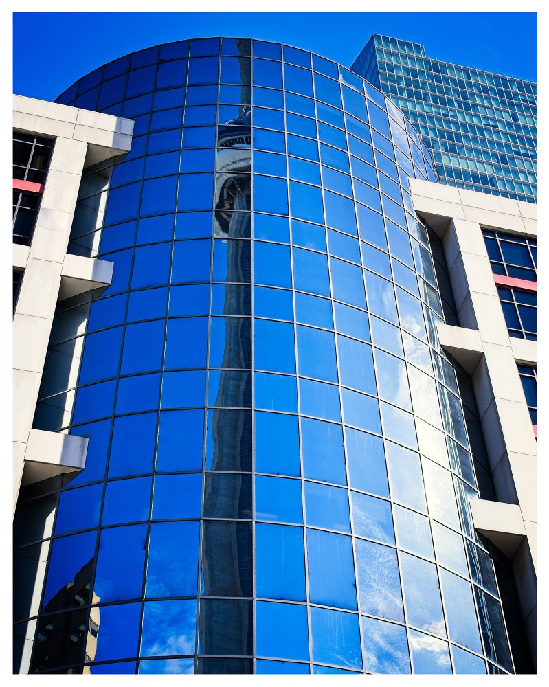 Curved reflection of the CN Tower in Toronto, Canada. Clear blue skies.