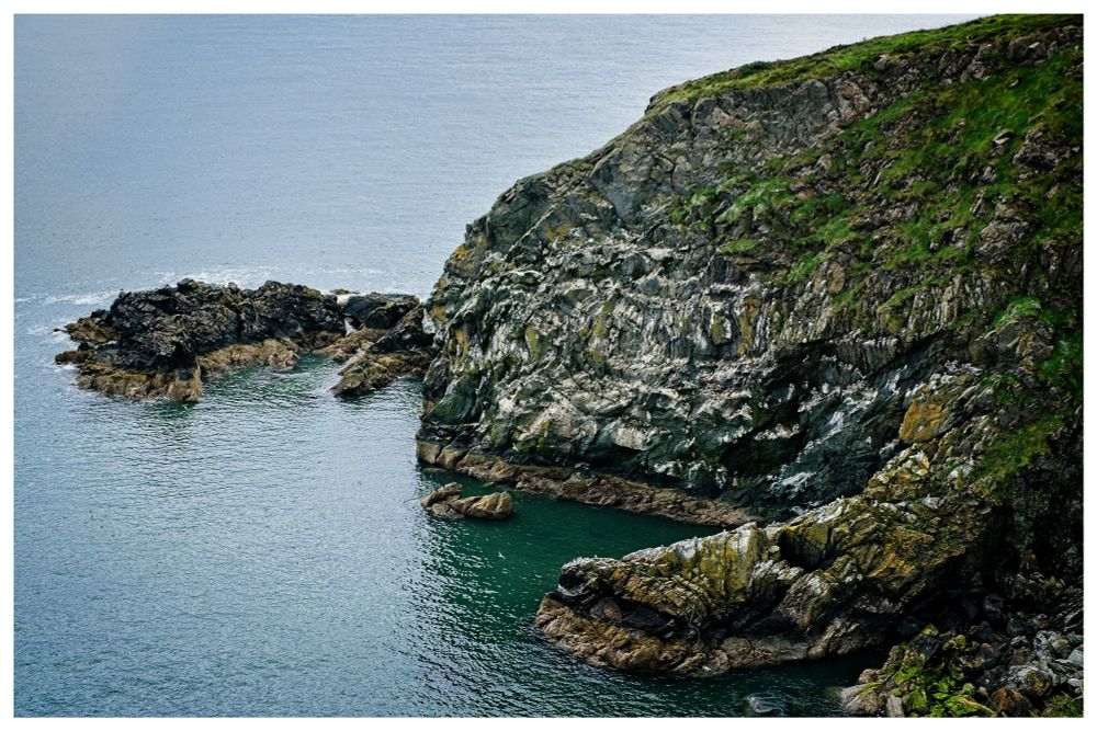 Looking down at the cliffs of Howth in Ireland. Cliff looks like a crab reaching into the ocean.
