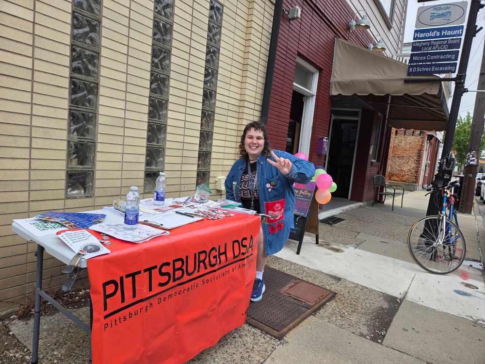 Me posing by a table representing the Pittsburgh DSA (Democratic Socialists of America)