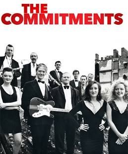 Photo/picture of the poster for the Alan Parker film, 'The Commitments'. The title is in red. There is a photo in black and white of the eleven band members, dressed in tuxedo suits (male) or cocktail dresses (female), standing on waste ground, looking directly to camera.