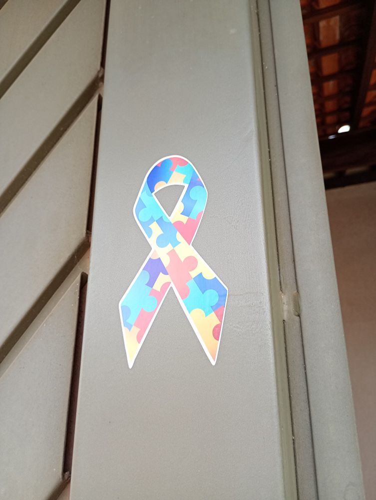 Portão com um adesivo de laço com quebra cabeças que é o símbolo mais conhecido do autismo 