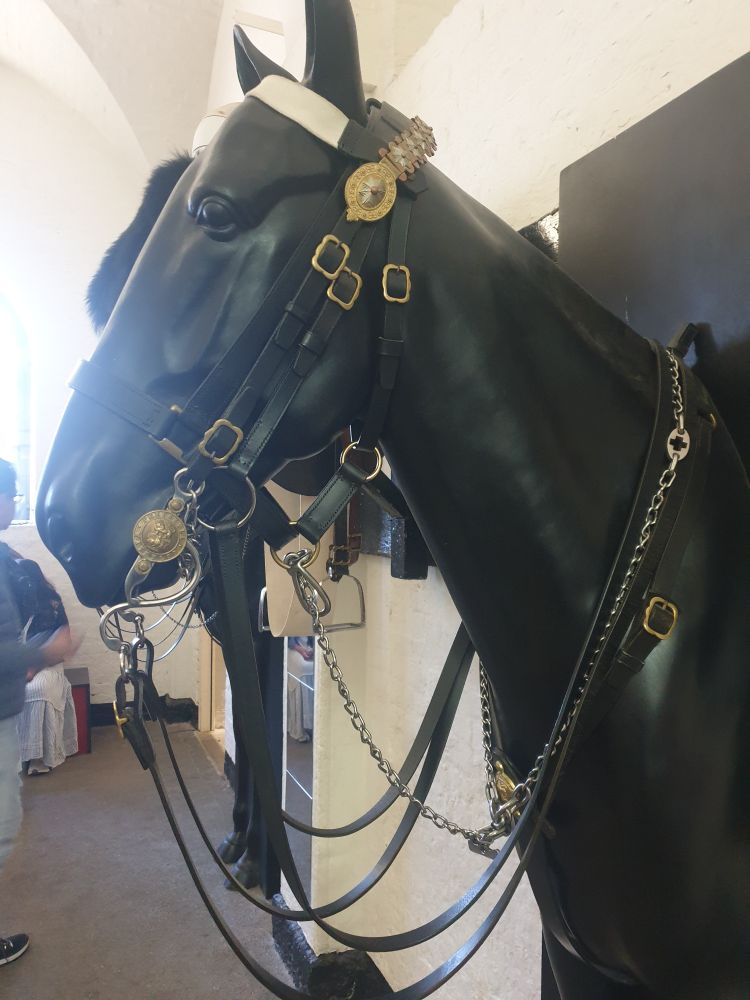 A complex bridle being worn by a black horse statue.