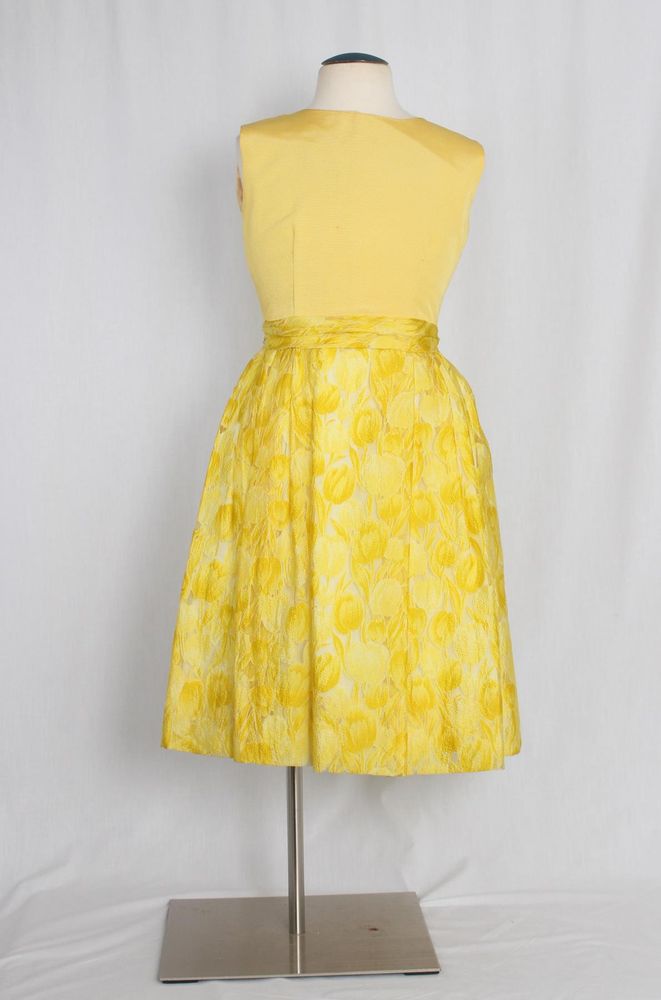 Dress of yellow cotton and yellow synthetic cloth woven with tulip motif: jewel neckline; sleeveless; CB zipper closure; natural waist, attached sash waist F; full skirt, gathered to waist; below knee length.