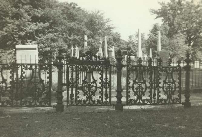 Black and white photograph showing iron fence enclosing monuments at Hollywood Cemetery; trees in background; "Hollywood Cemetery" written at bottom of photo; "A2-4 / Hollywood" written on reverse; Richmond, Virginia.
