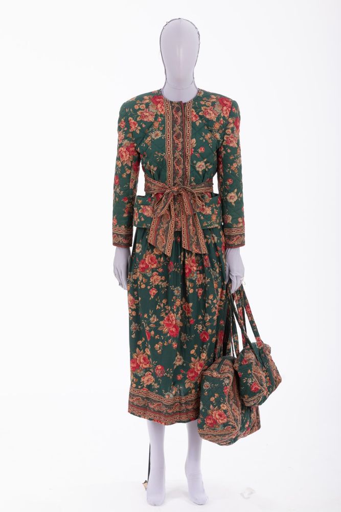 Ensemble composed of jacket, skirt, belt, shoulder bag, and handbag of green cotton with printed "Greenbriar" floral motif with tortoiseshell buttons: a) quilted jacket: round neck; long sleeves, contrast pattern band cuffs; CF button closure; contrast pattern bands CF; patch pocket L and R hips; hip length; fully lined; b) dirndl skirt: full skirt, gathered; calf length; contrast pattern hem; c) belt: contrast pattern; tie closure; d) quilted shoulder bag: patch pocket; zipper closure; e) quilted handbag: patch pocket; zipper closure.