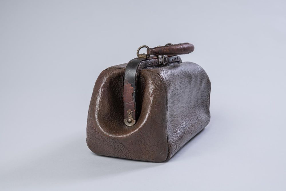 MEDICAL BAG; reddish brown leather; metal hinged opening and metal clasp in top; leather handle.