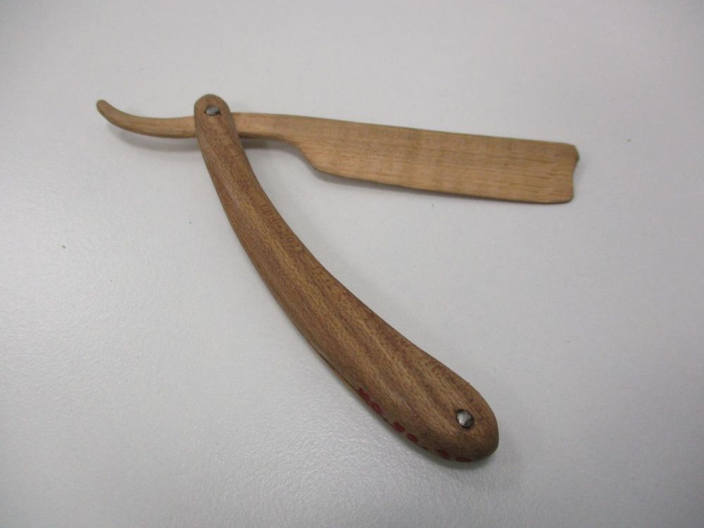 Folding novelty straight razor made entirely of wood, darkwood (possibly walnut) for the curved handle and lightwood (possibly maple) for the rectangular blade and neck. Blade swivels on metal hinge pin on one end to store folded between each half of the curved handle. Gift of Miss Coralie Johnston; razor was made by Ty Powman of Washington County, VA, for Dr. George Ben Johnston.